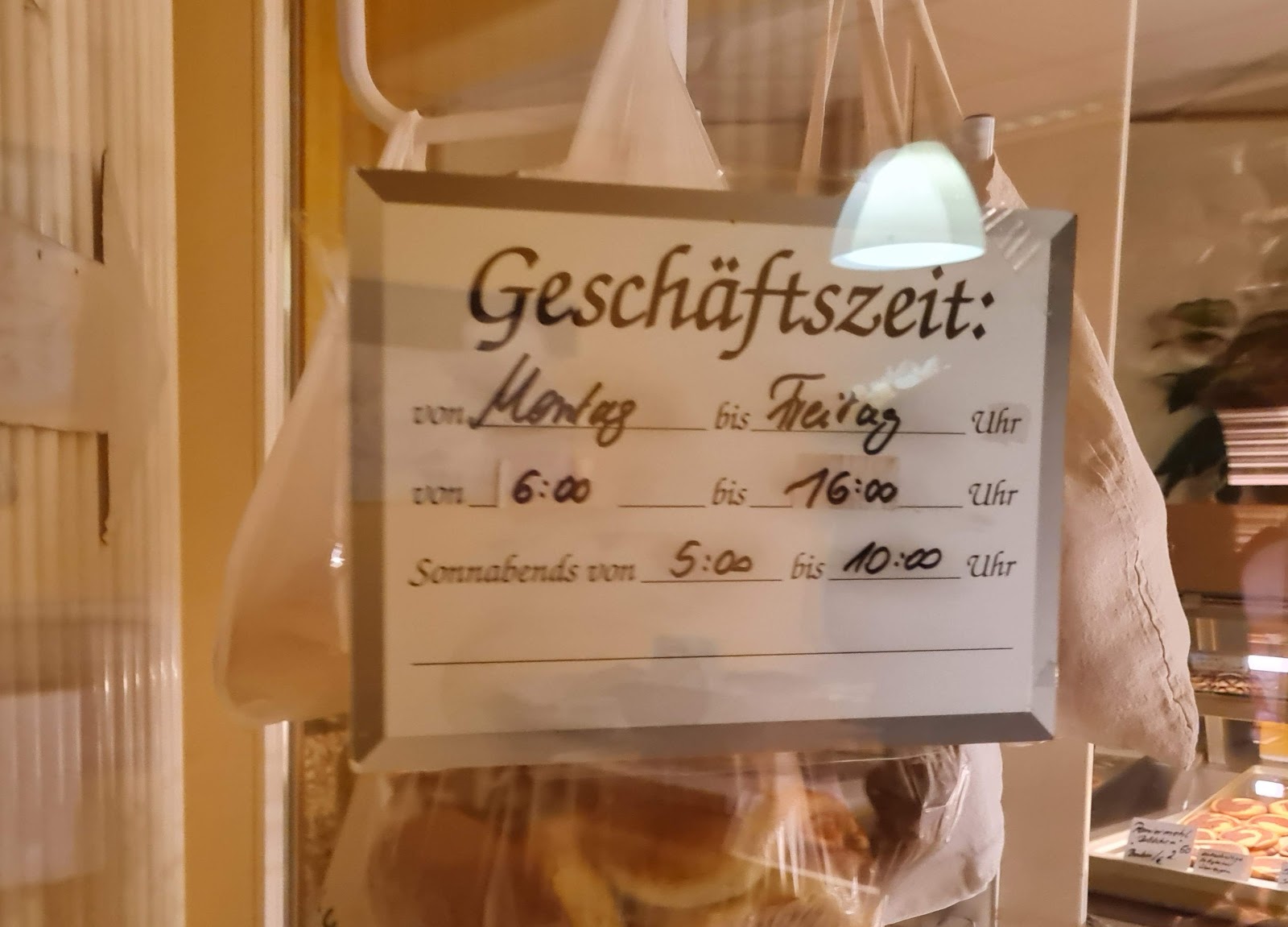 Handgeschriebenes Öffnungszeiten-Schild im Schaufenster der Feinbäckerei Gruttke